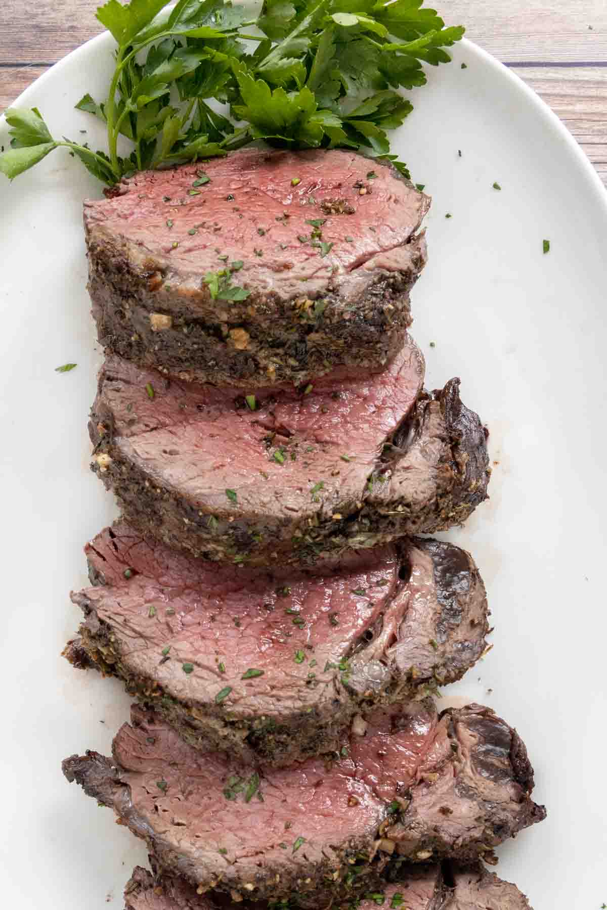 Sliced roasted beef tenderloin on a white platter