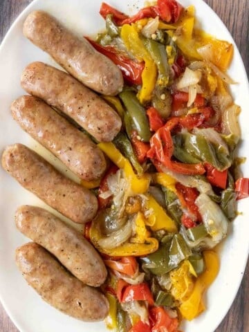 Italian sausage, peppers, and onions on a white platter.