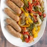 Italian sausage, peppers, and onions on a white platter.