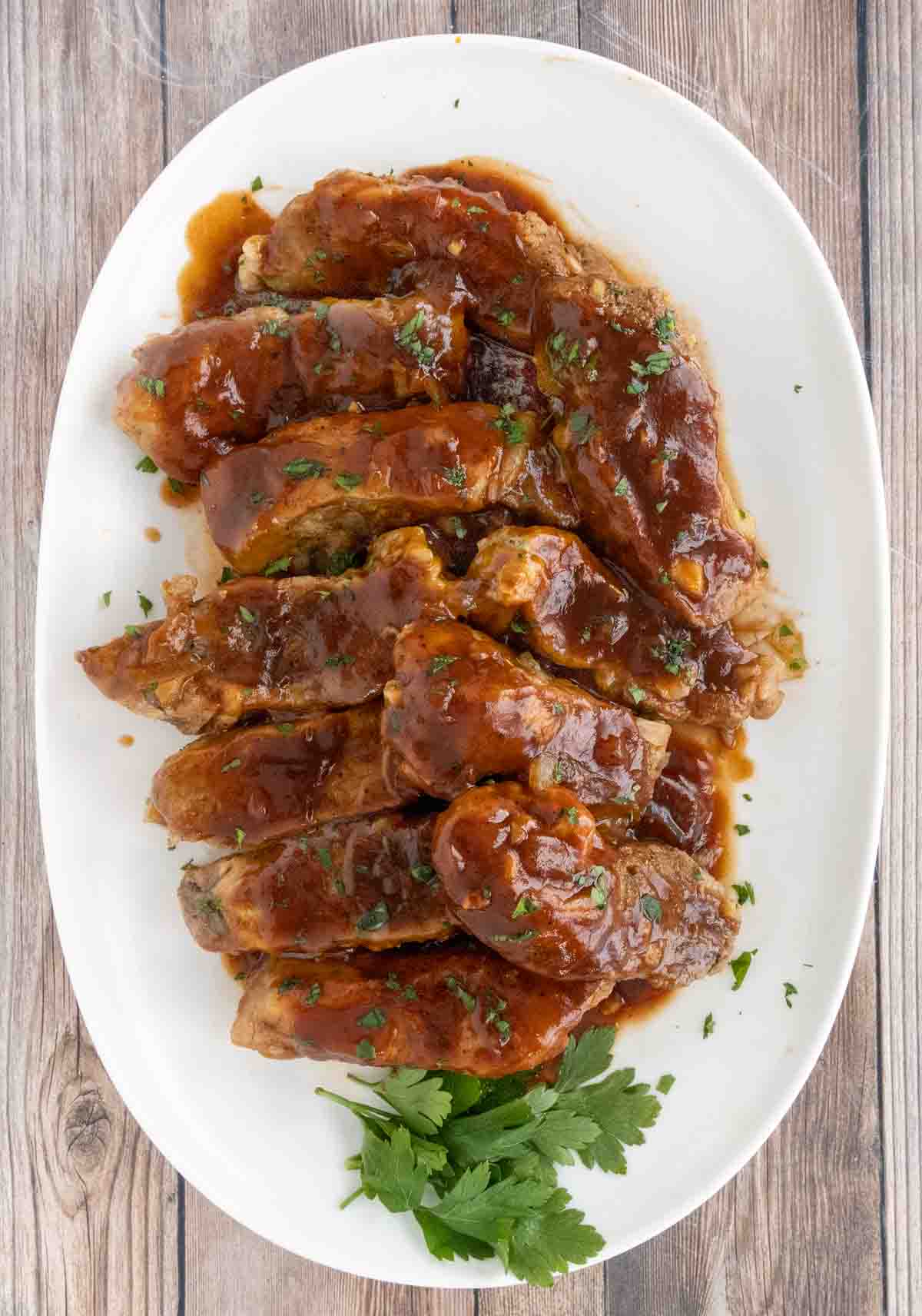 Slow cooker country style pork ribs on a white platter.