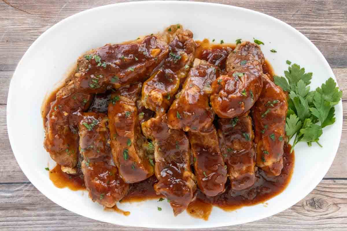 Slow cooker country style pork ribs on a white platter.