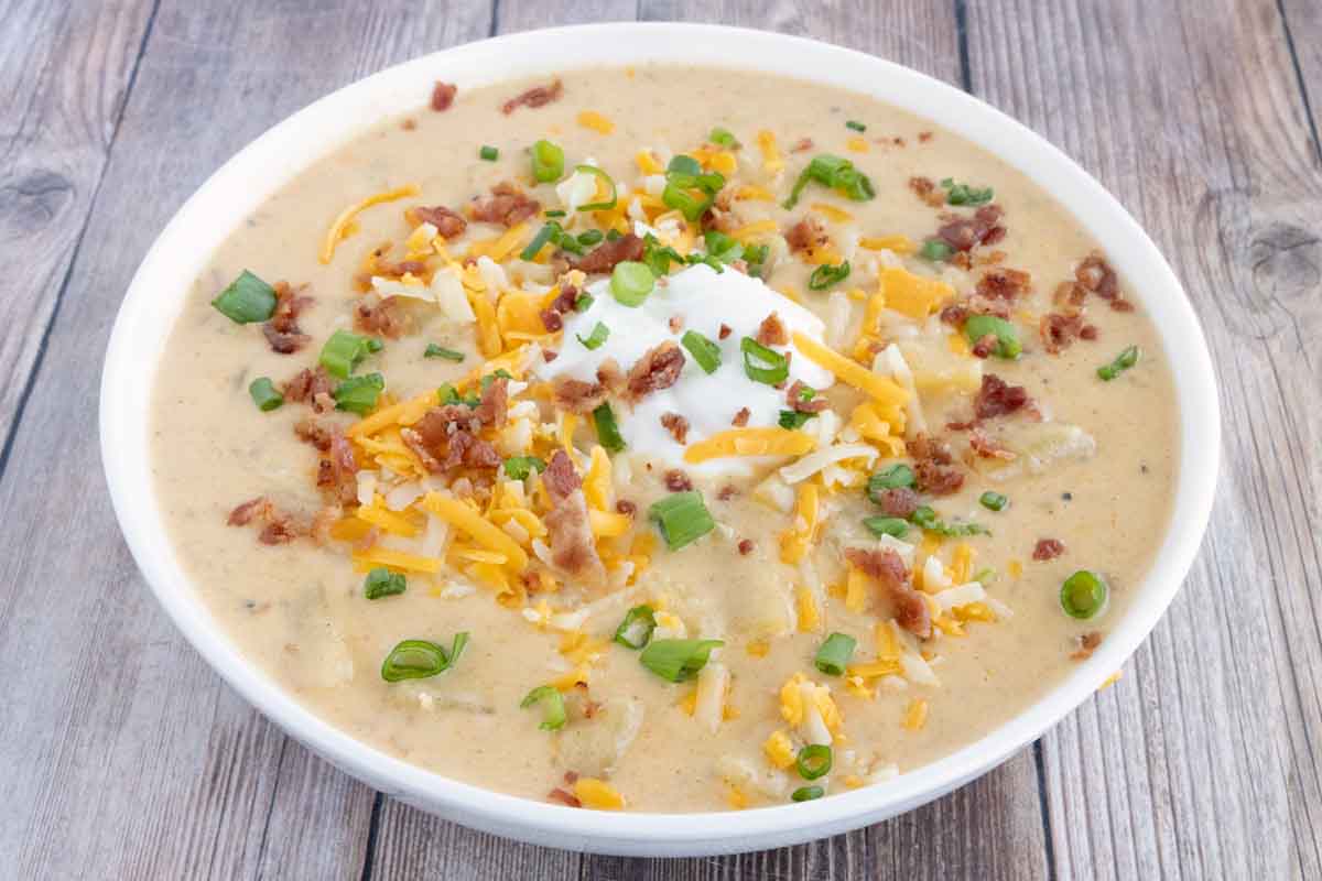 Slow cooker loaded potato soup in a white bowl.