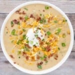Slow cooker loaded potato soup in a white bowl.