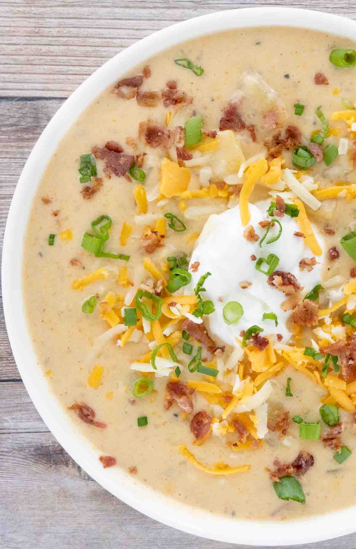 Slow cooker loaded potato soup in a white bowl.