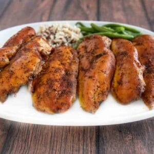 Smoked chicken breasts on a white platter.
