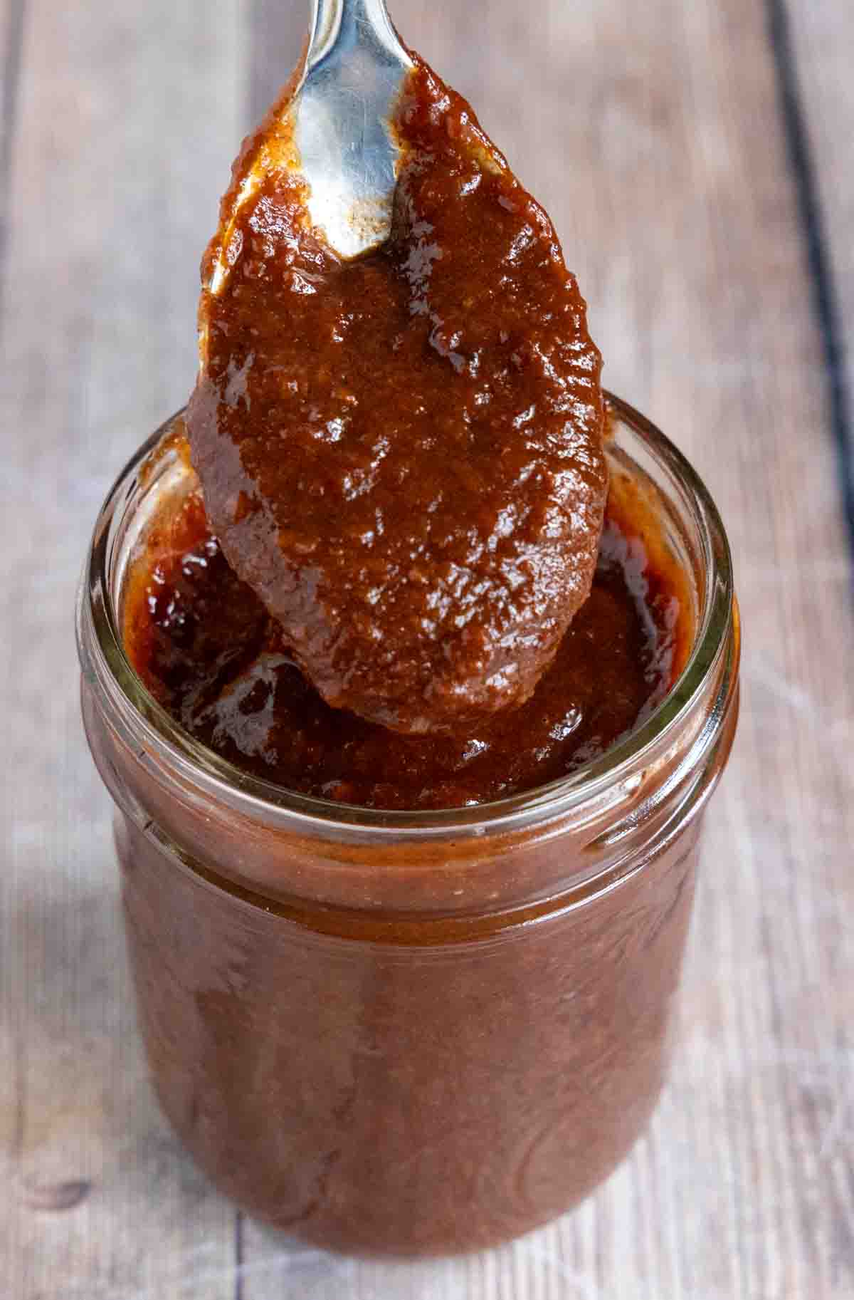 Chamoy sauce in a jar with a spoon coming out of the jar.