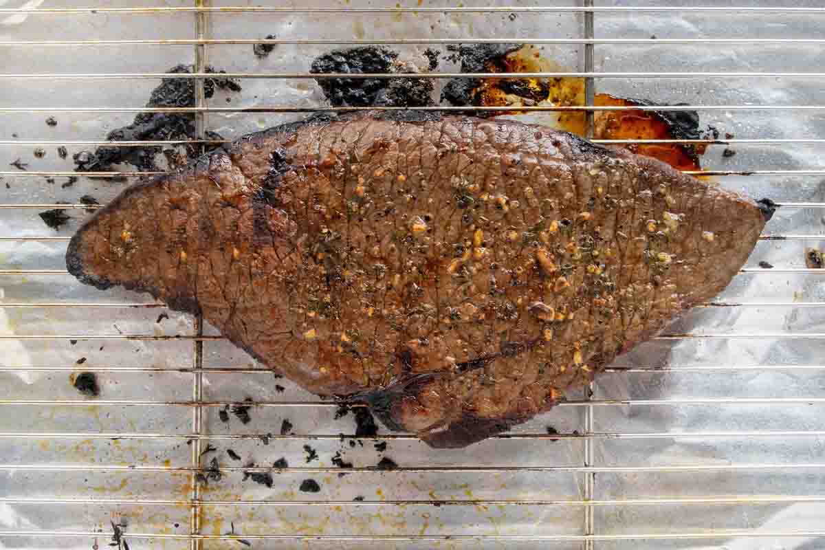 Fully cooked London broil on a wire rack.