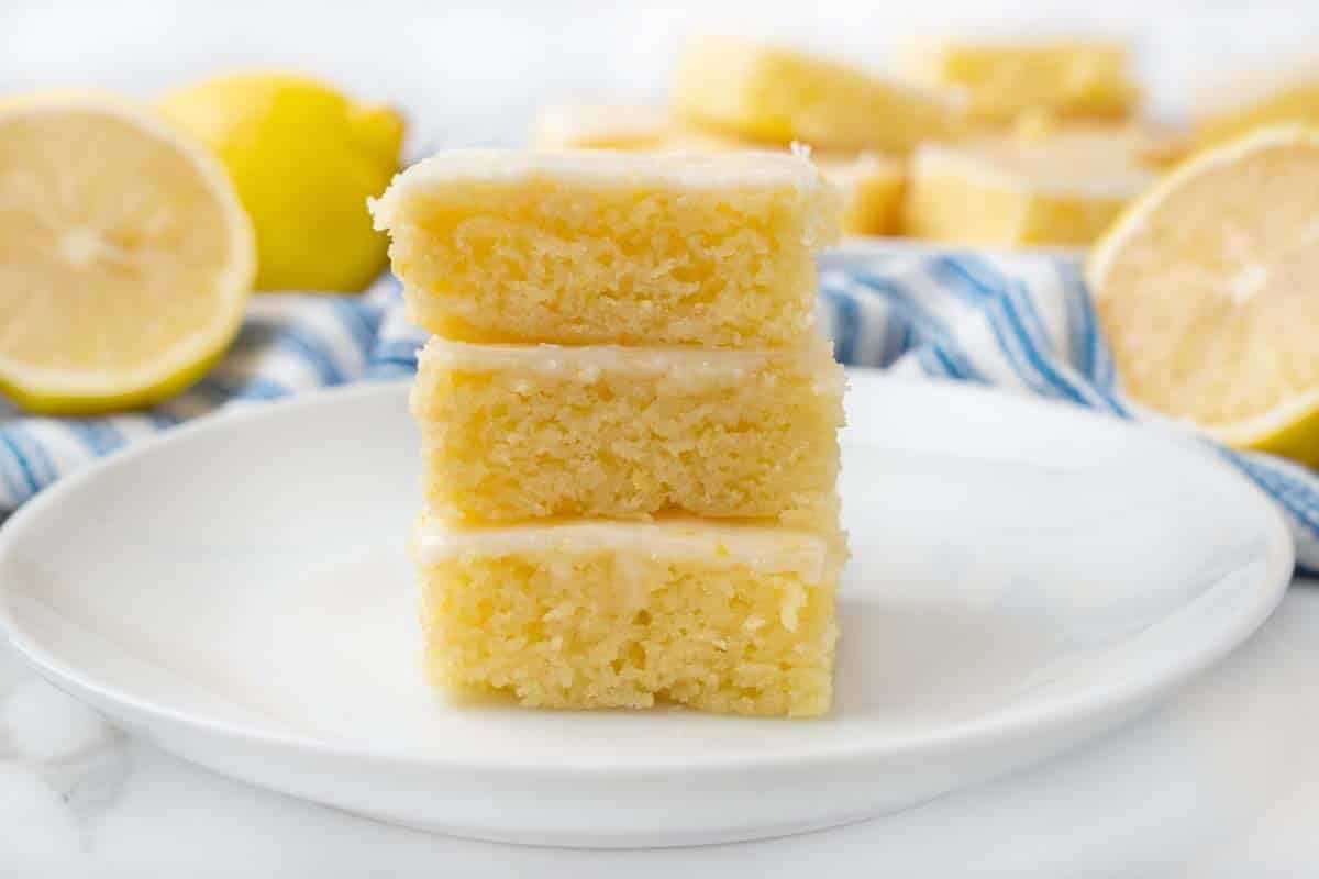 Three lemon brownies stacked on a white plate.