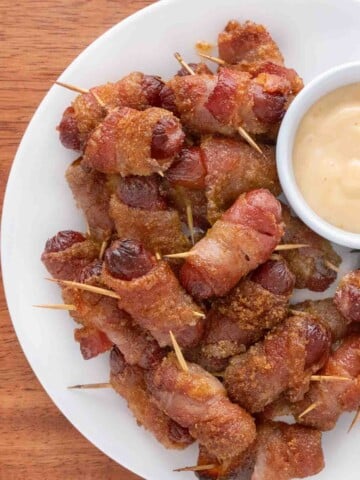 Bacon wrapped smokies on a white plate.