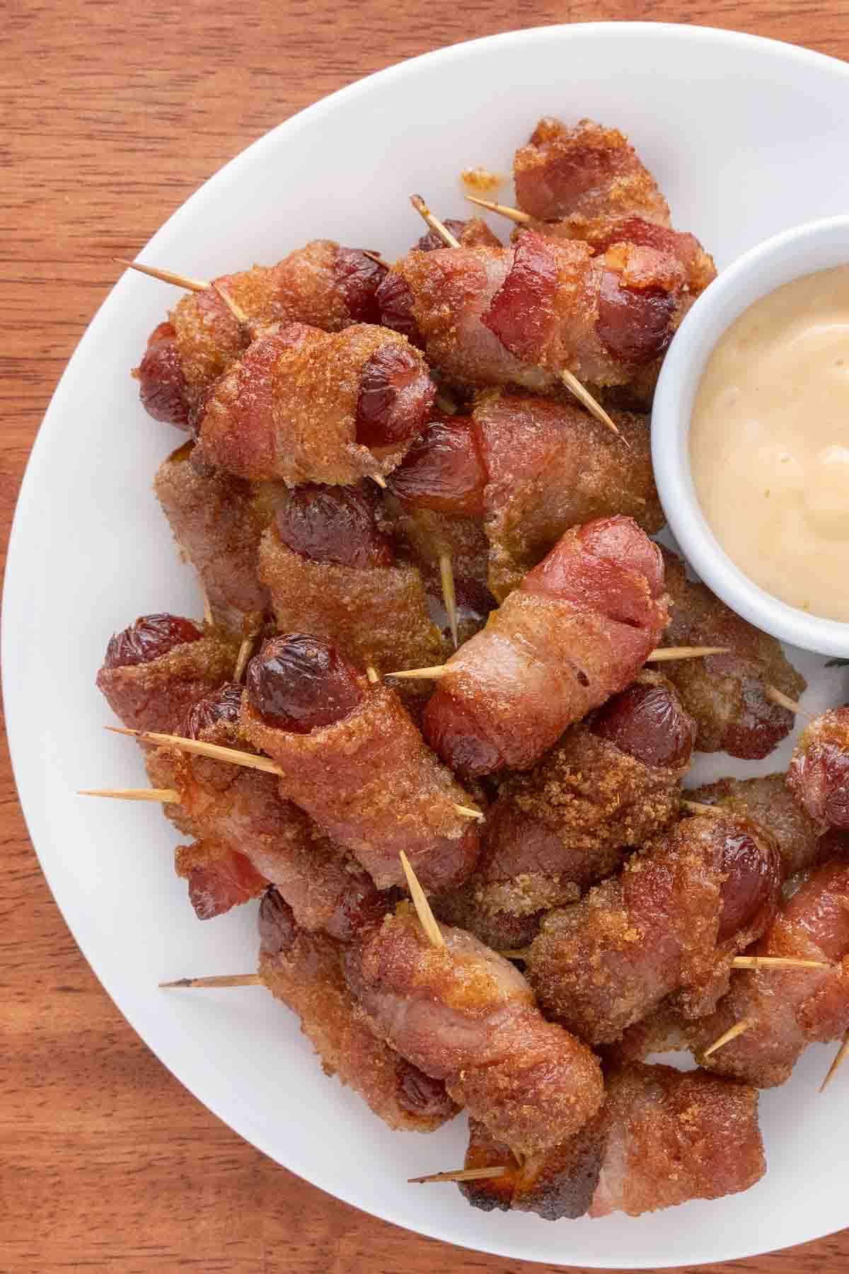 Bacon wrapped smokies on a white plate.