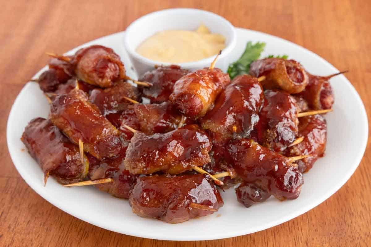 Bacon wrapped smokies with barbecue sauce on a white plate.