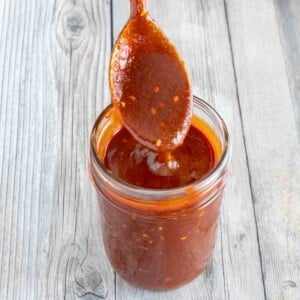 Gochujang Sauce in a glass jar with a spoon coming out.