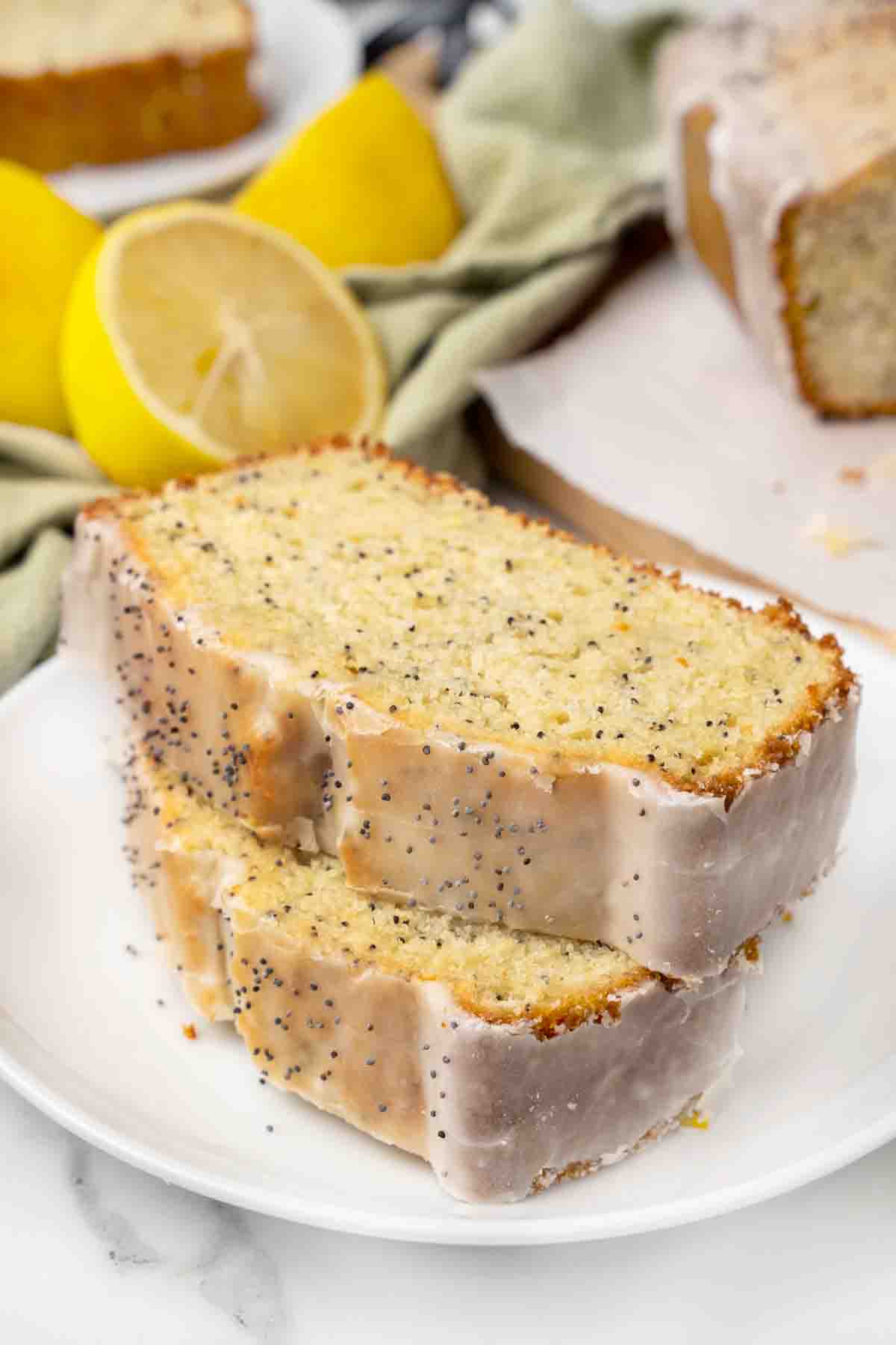 2 Slices of lemon poppy seed cake stacked on a white plate.