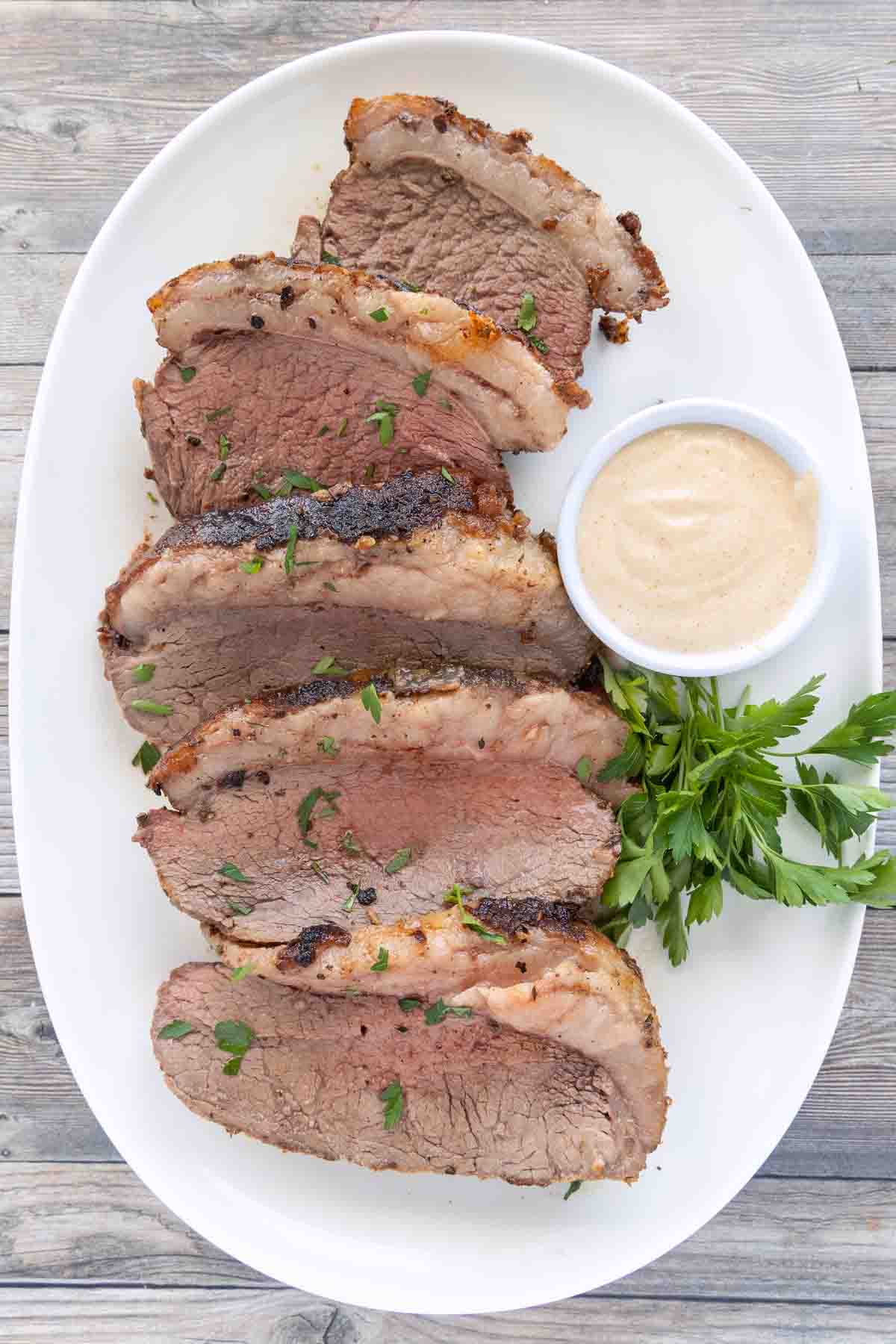 Sliced picanha roast on a white platter.