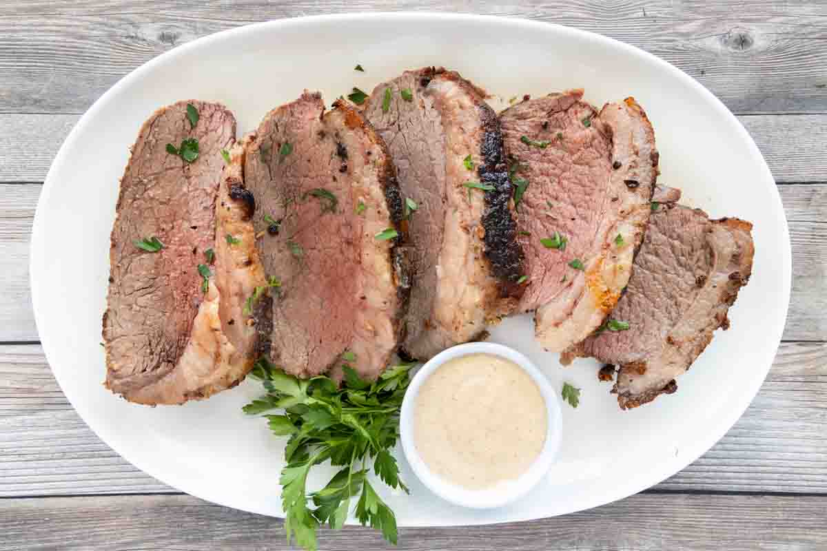 Sliced picanha roast on a white platter.
