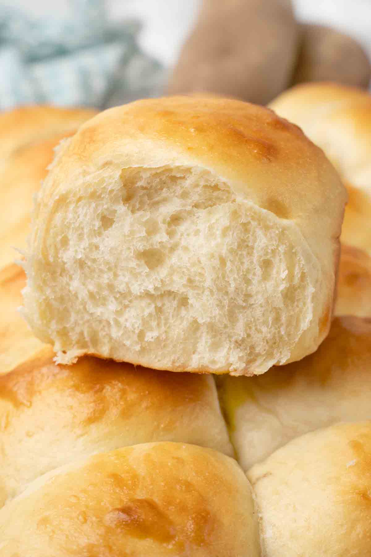 Close up of potato dinner roll on top of the other rolls.