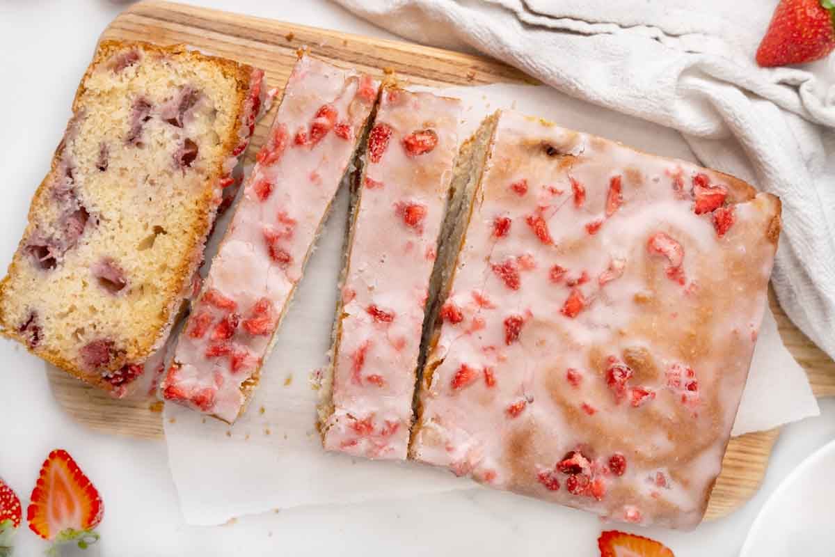 Sliced strawberry bread on white paper on a cutting board.