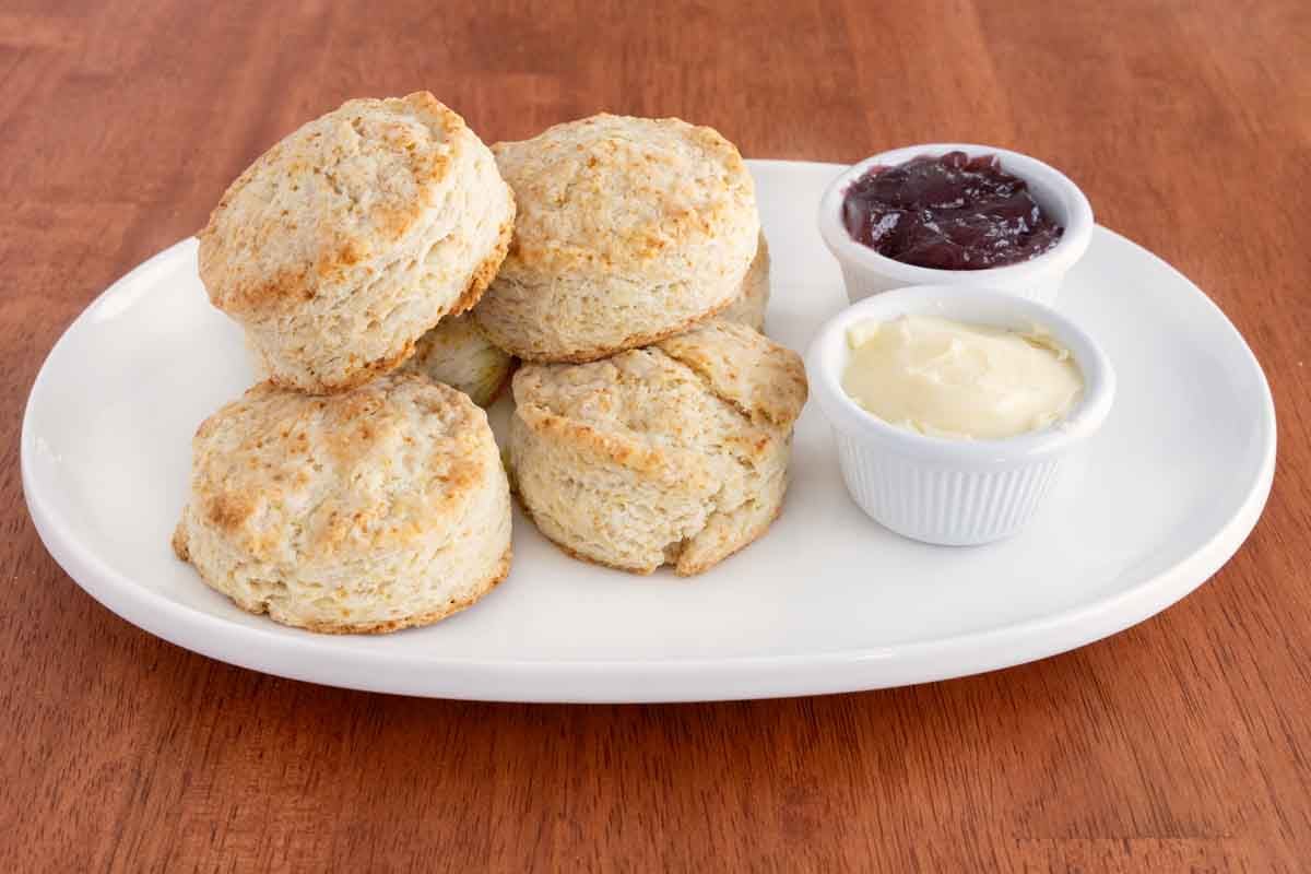 Homemade biscuits with butter and jam on a white plate.