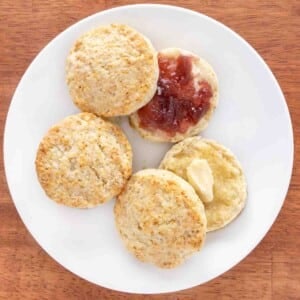 Homemade biscuits with butter and jam on a white plate.