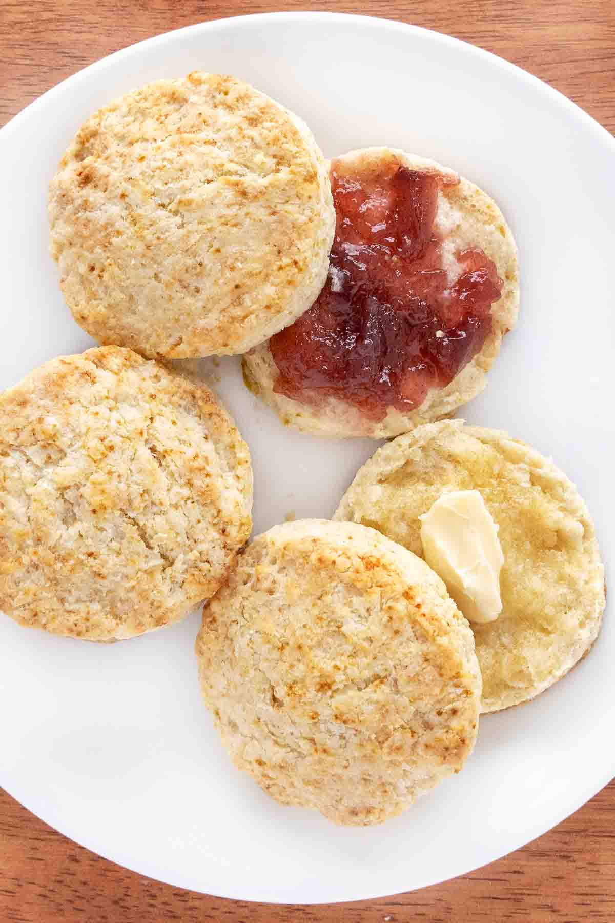 Homemade biscuits with butter and jam on a white plate.