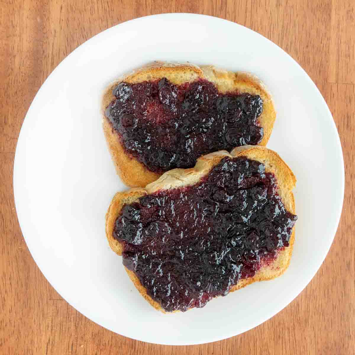 Blueberry jam on toast on a white plate.