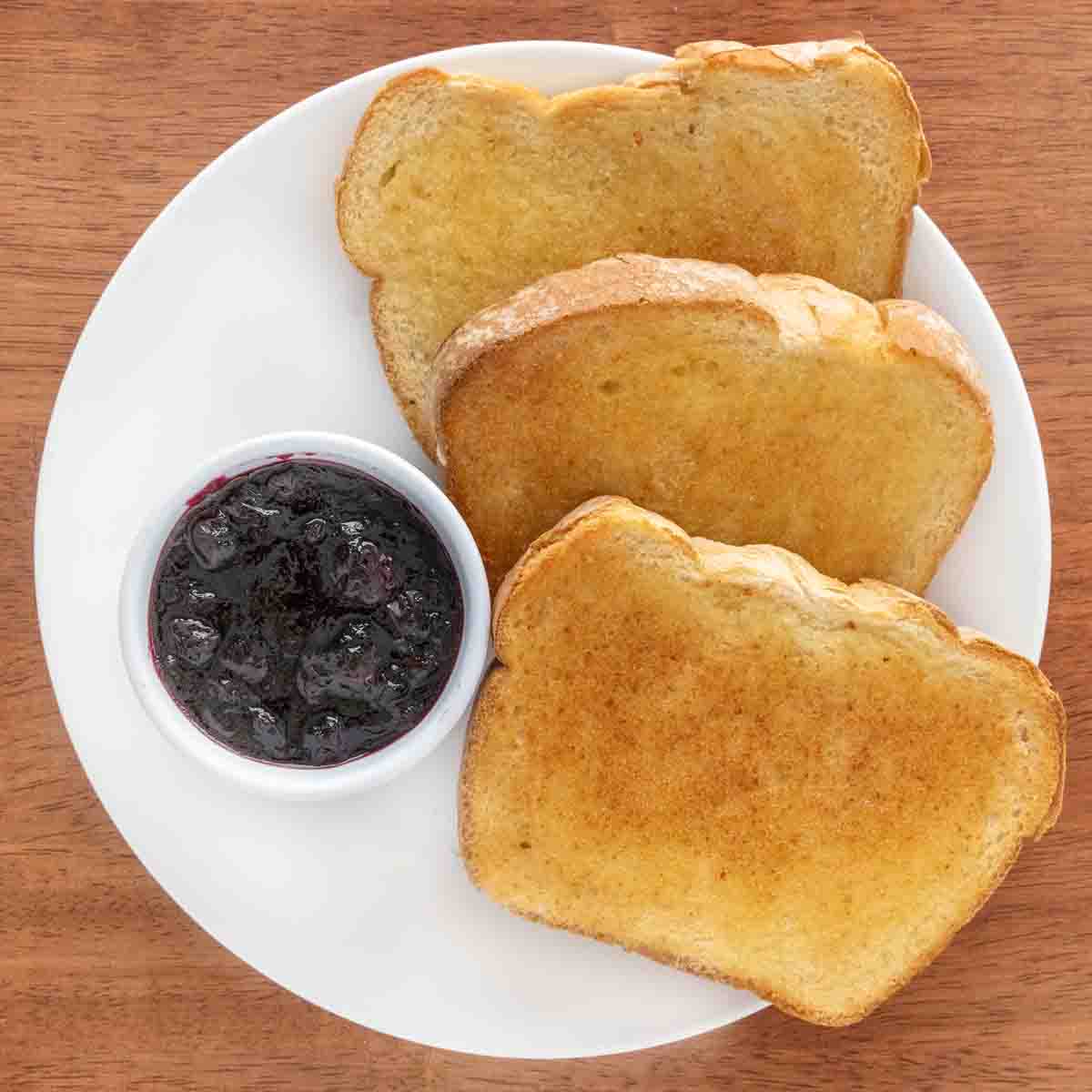 Blueberry jam and toast on a white plate.