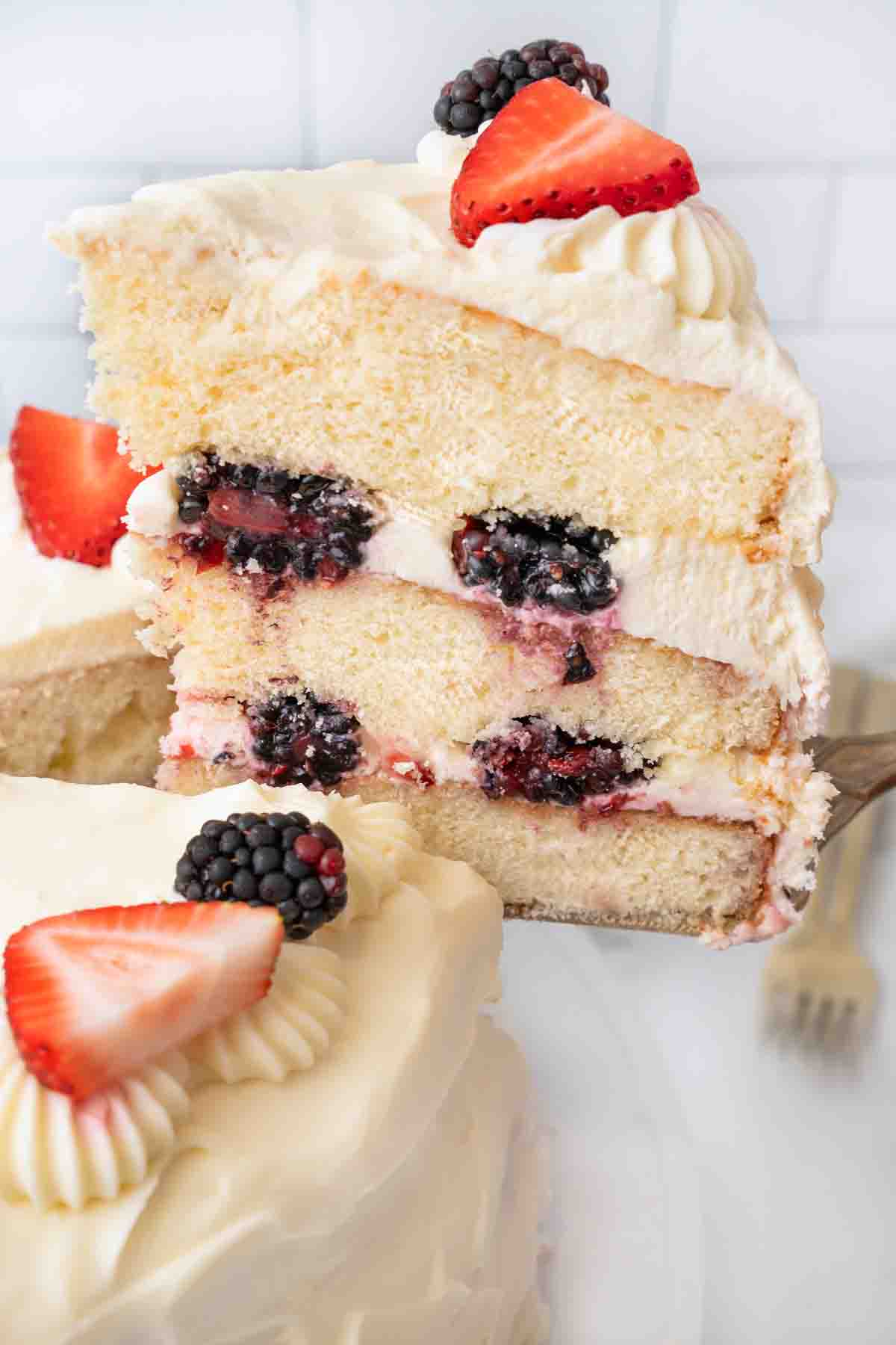 Slice of Chantilly cake being taken out of the whole cake.