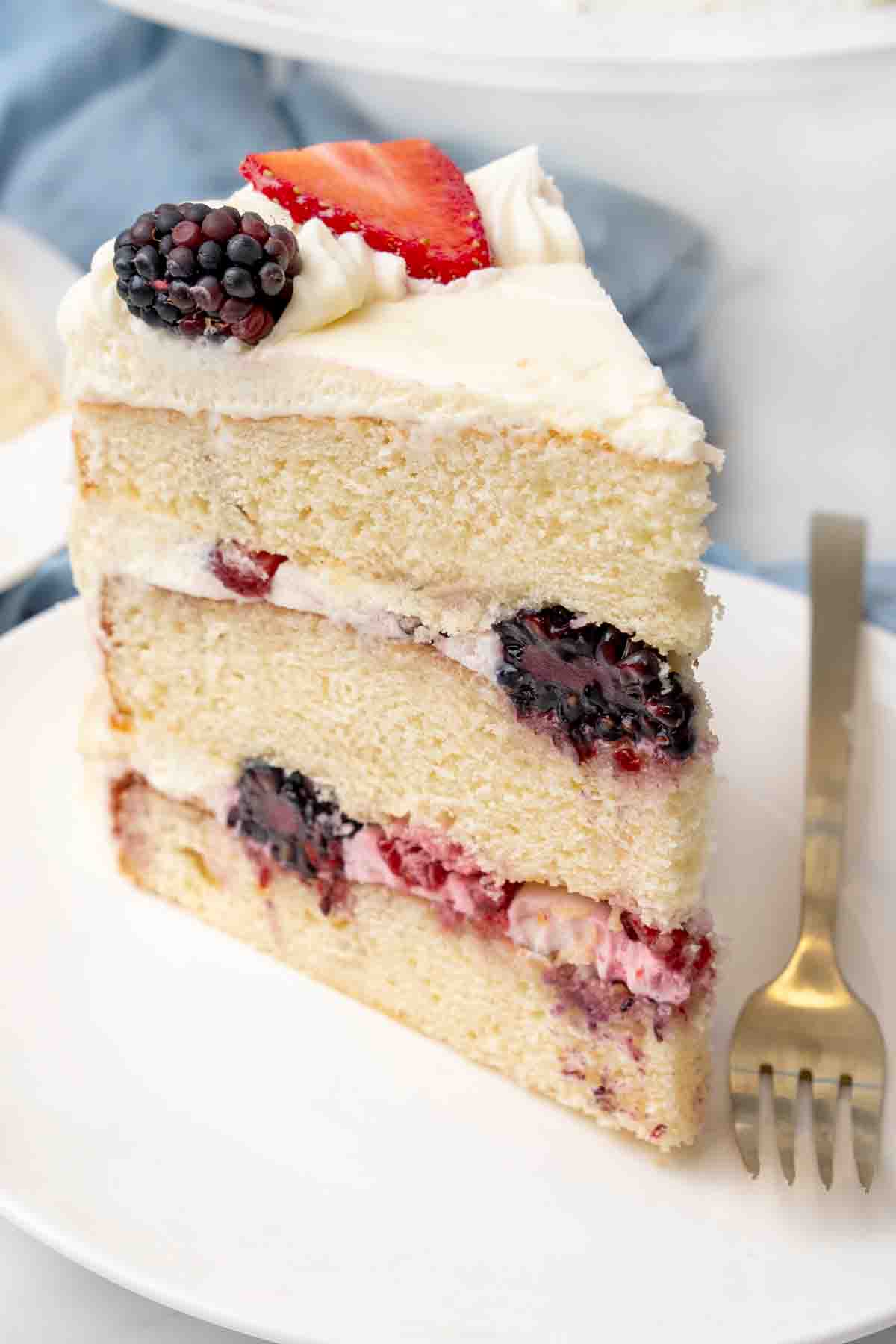 Slice of Chantilly cake on a white plate.