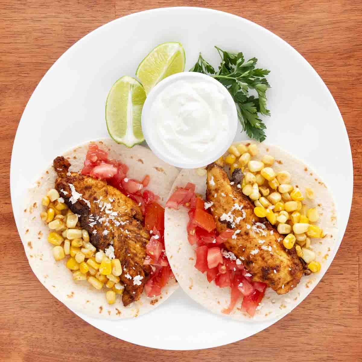 Chicken tacos on a white plate.