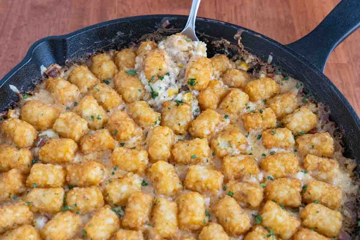 Cowboy casserole with a spoon coming out of a cast-iron pan