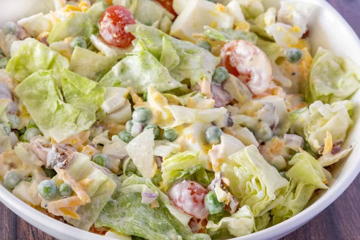 Seven layer salad in a white bowl.