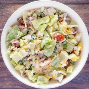 Seven layer salad in a white bowl.