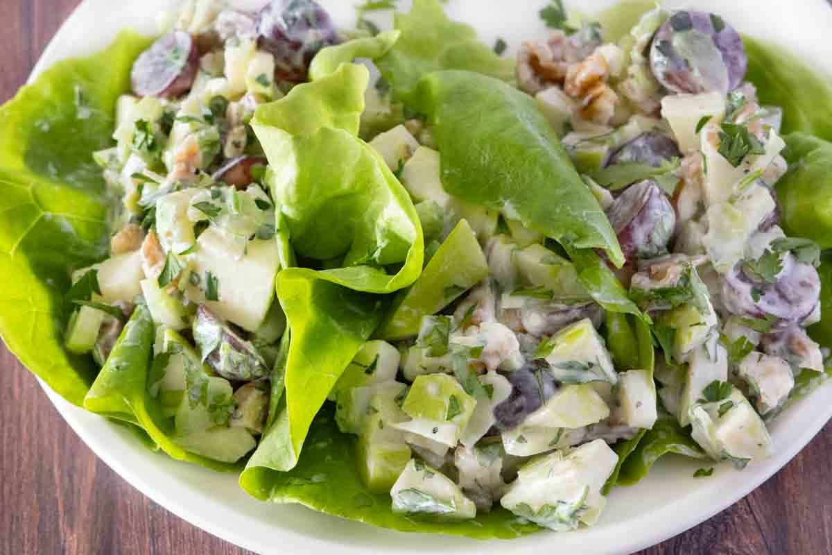 Waldorf salad in lettuce cups on a white plate.