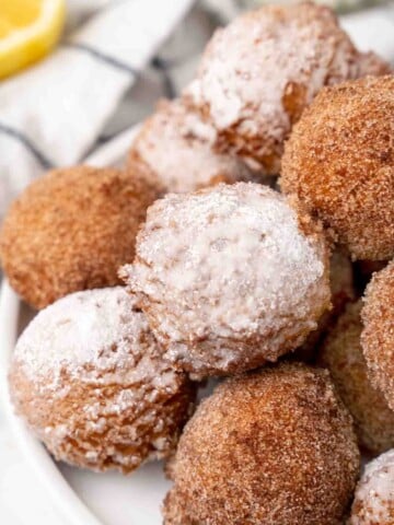 Zeppole stacked on a white plate.