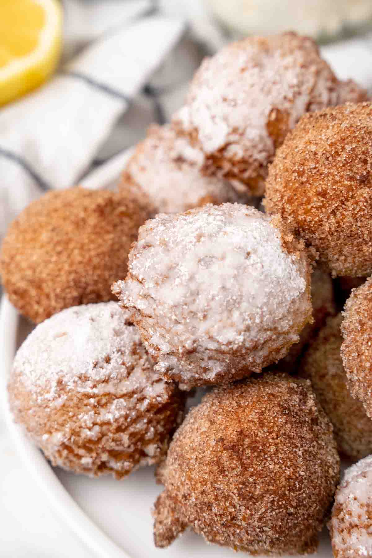 Zeppole stacked on a white plate.