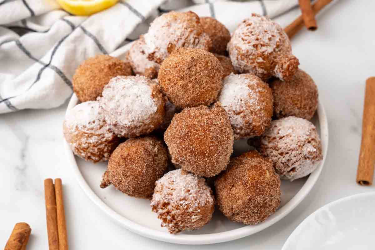 Zeppole stacked on a white plate.