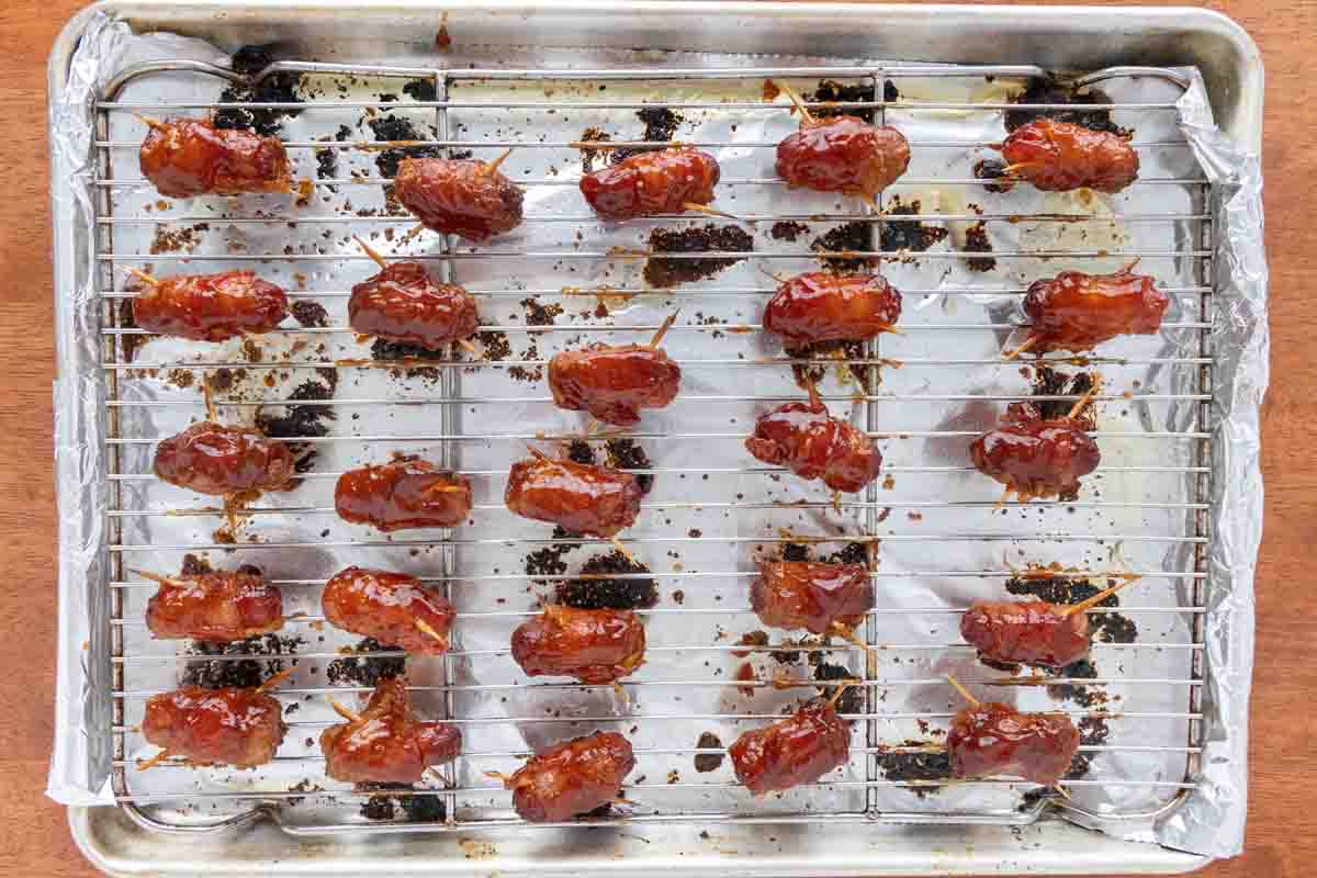 Bacon wrapped smokies with barbecue sauce on a sheet pan
