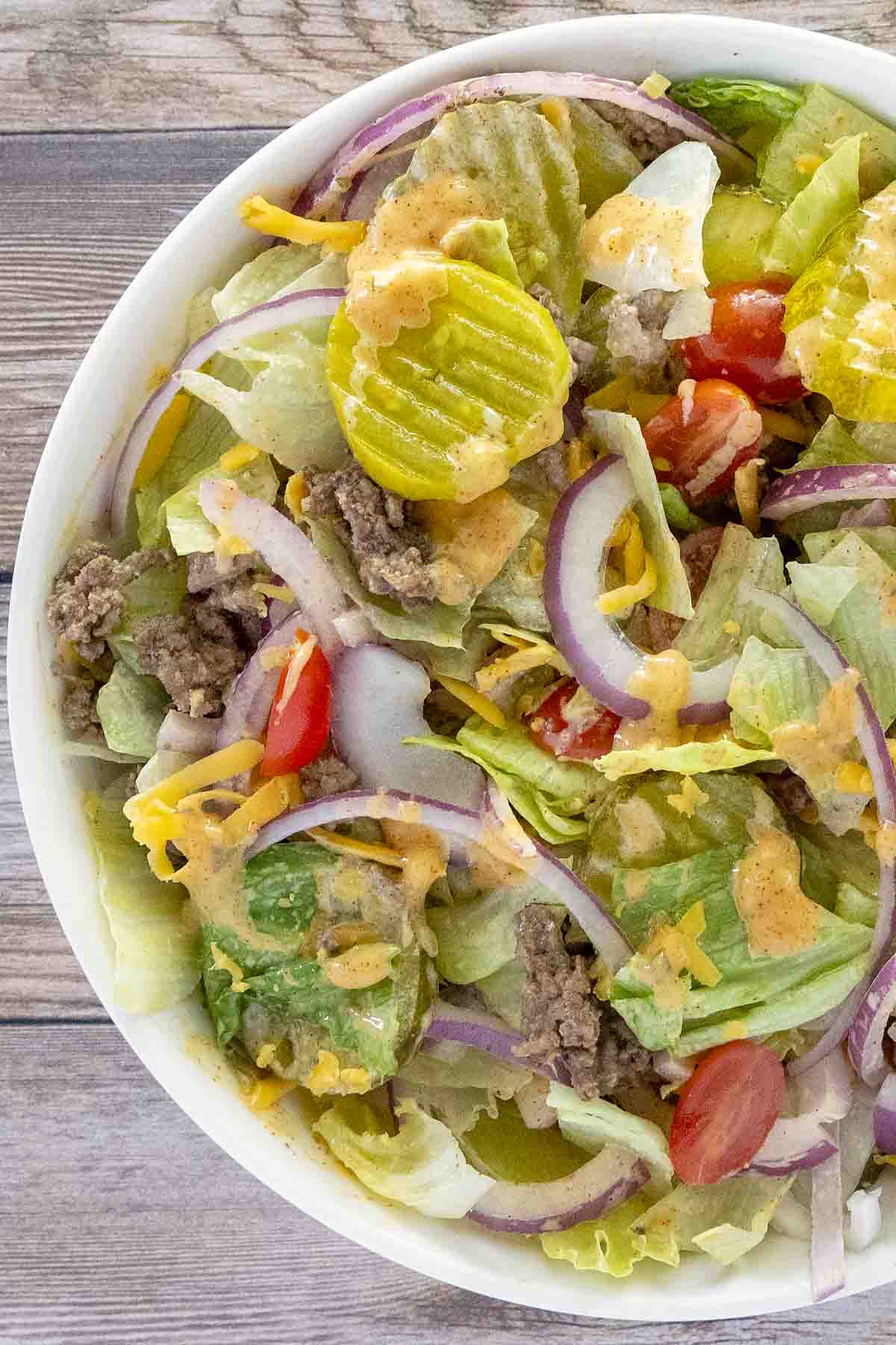 Big mac salad in a white bowl.