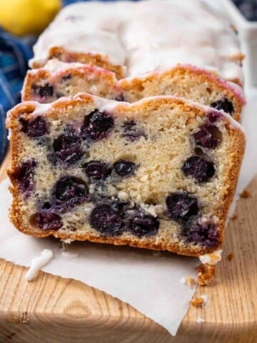 Sliced loaf of blueberry bread on a wooden cutting board.