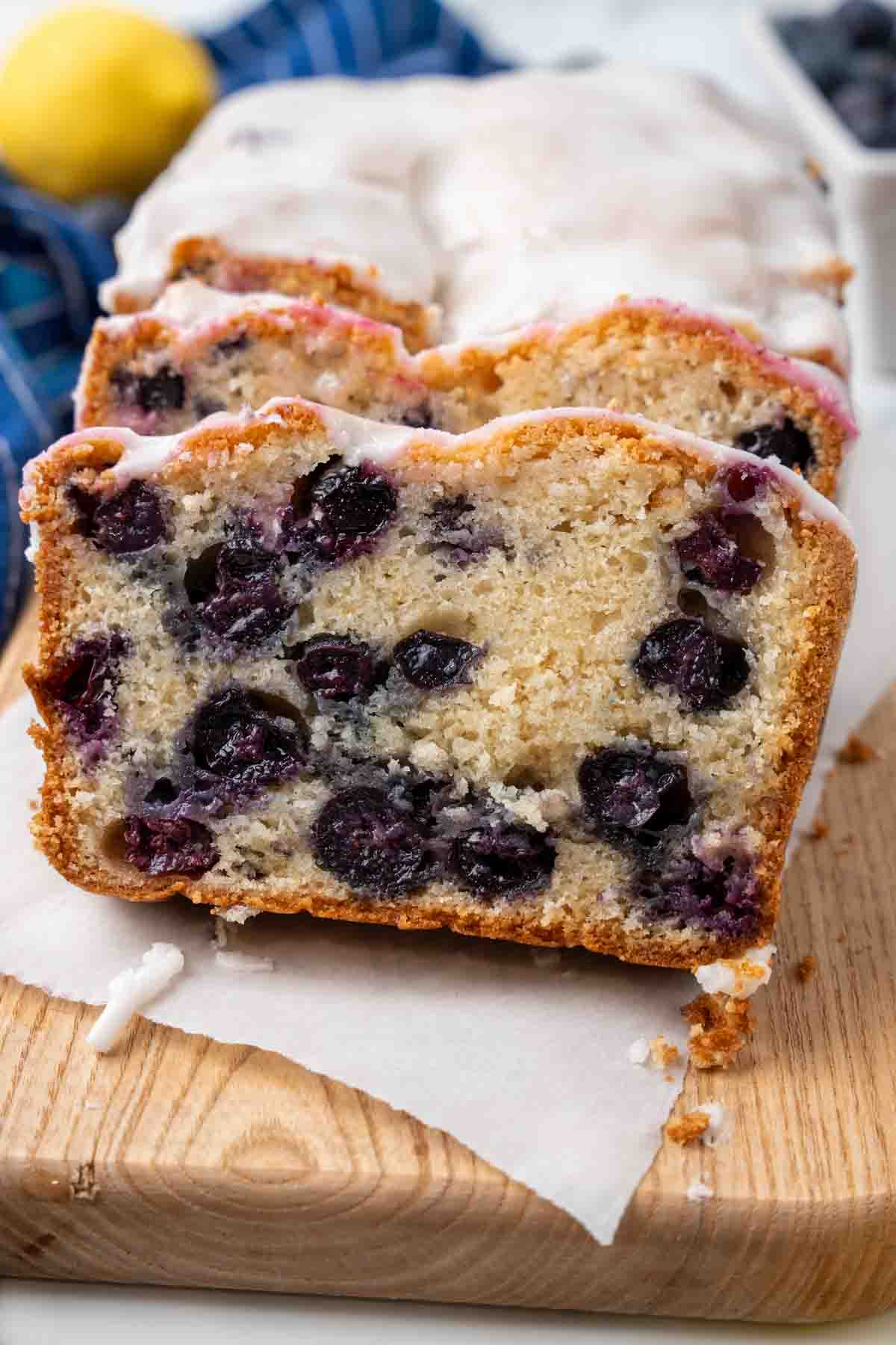 Sliced loaf of blueberry bread on a wooden cutting board.
