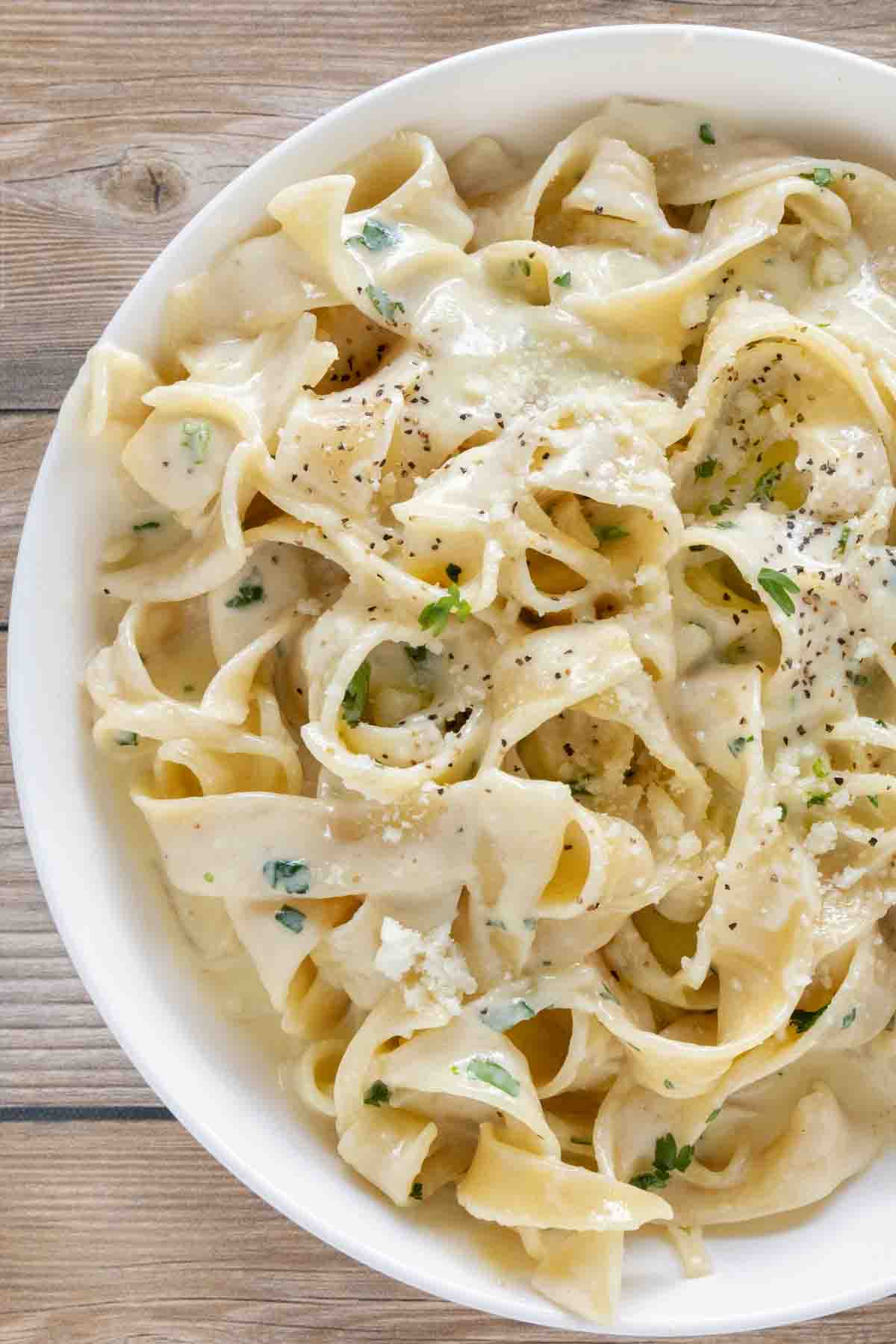 Alfredo sauce recipe served with homemade fettuccine in a white bowl.
