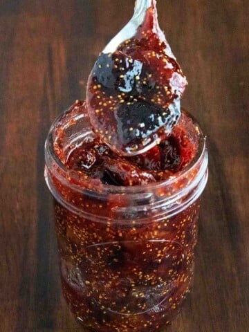 Fig jam in glass jar with spoon coming out.