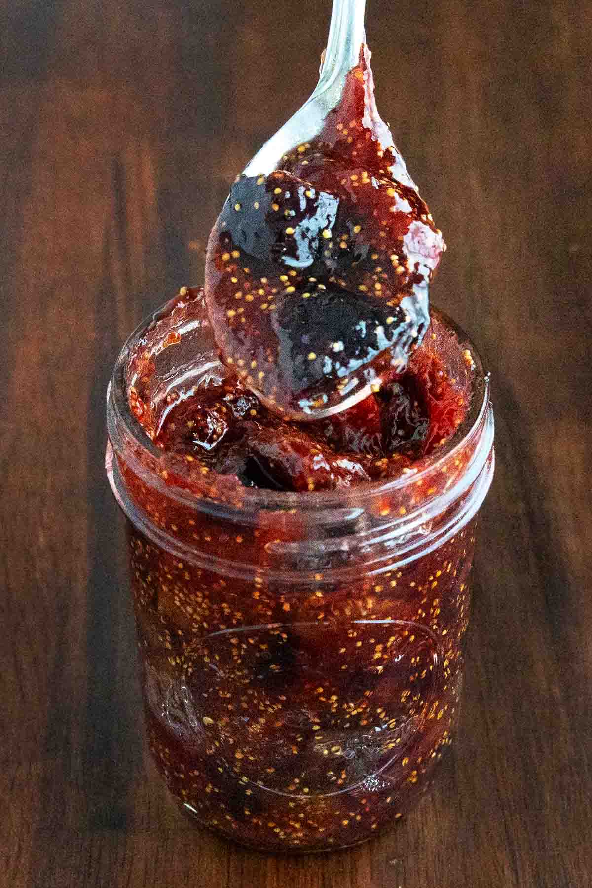 Fig jam in glass jar with spoon coming out.
