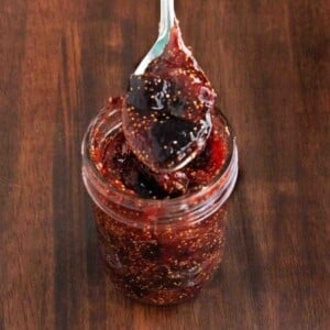 Fig jam in glass jar with spoon coming out.