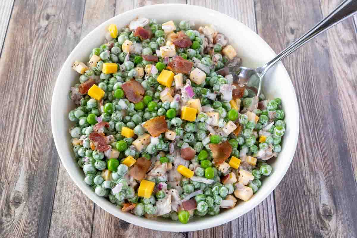 Green Pea Salad with a spoon coming out in a white bowl.