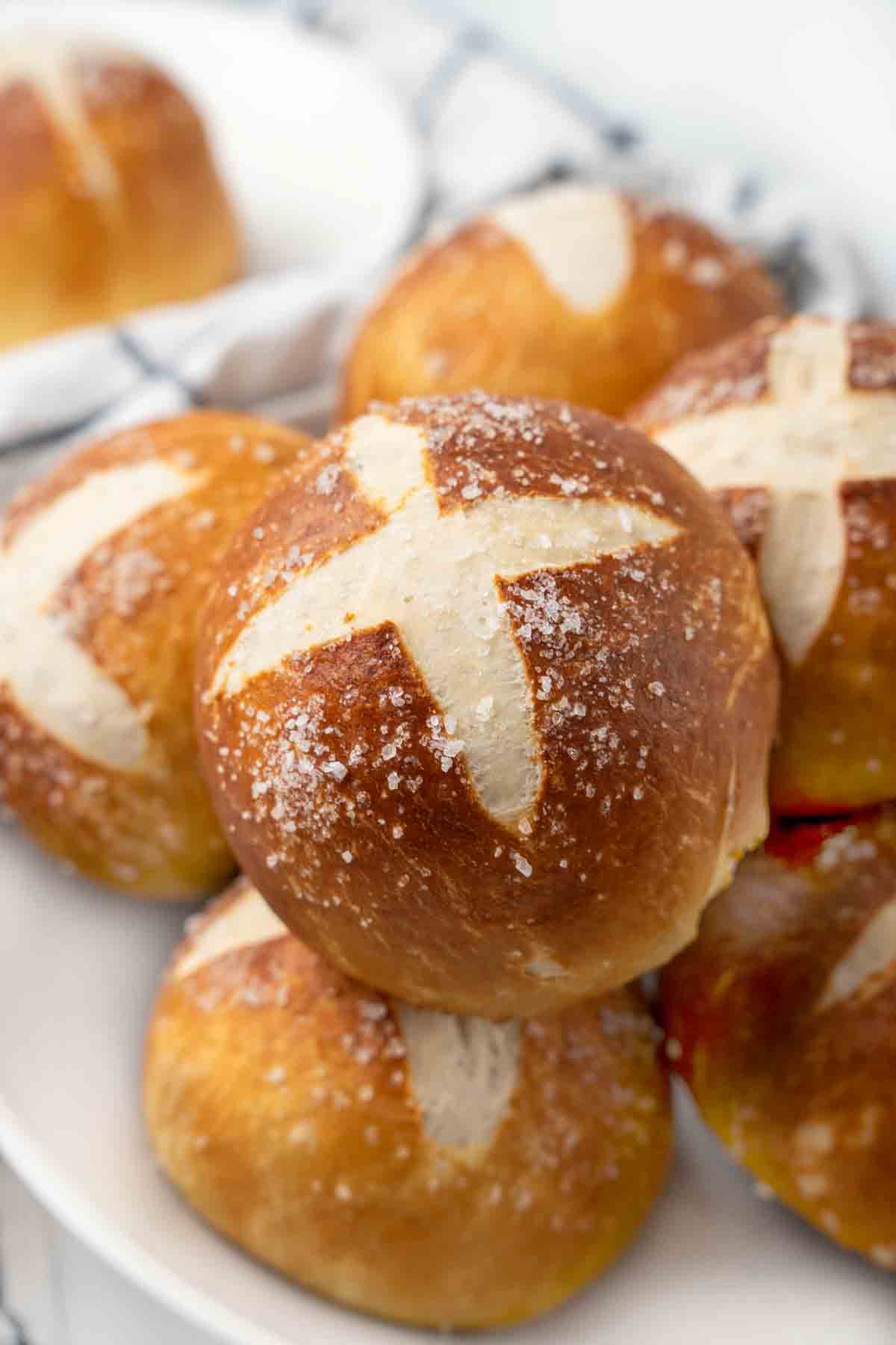 Pretzels rolls stacked on a white platter.