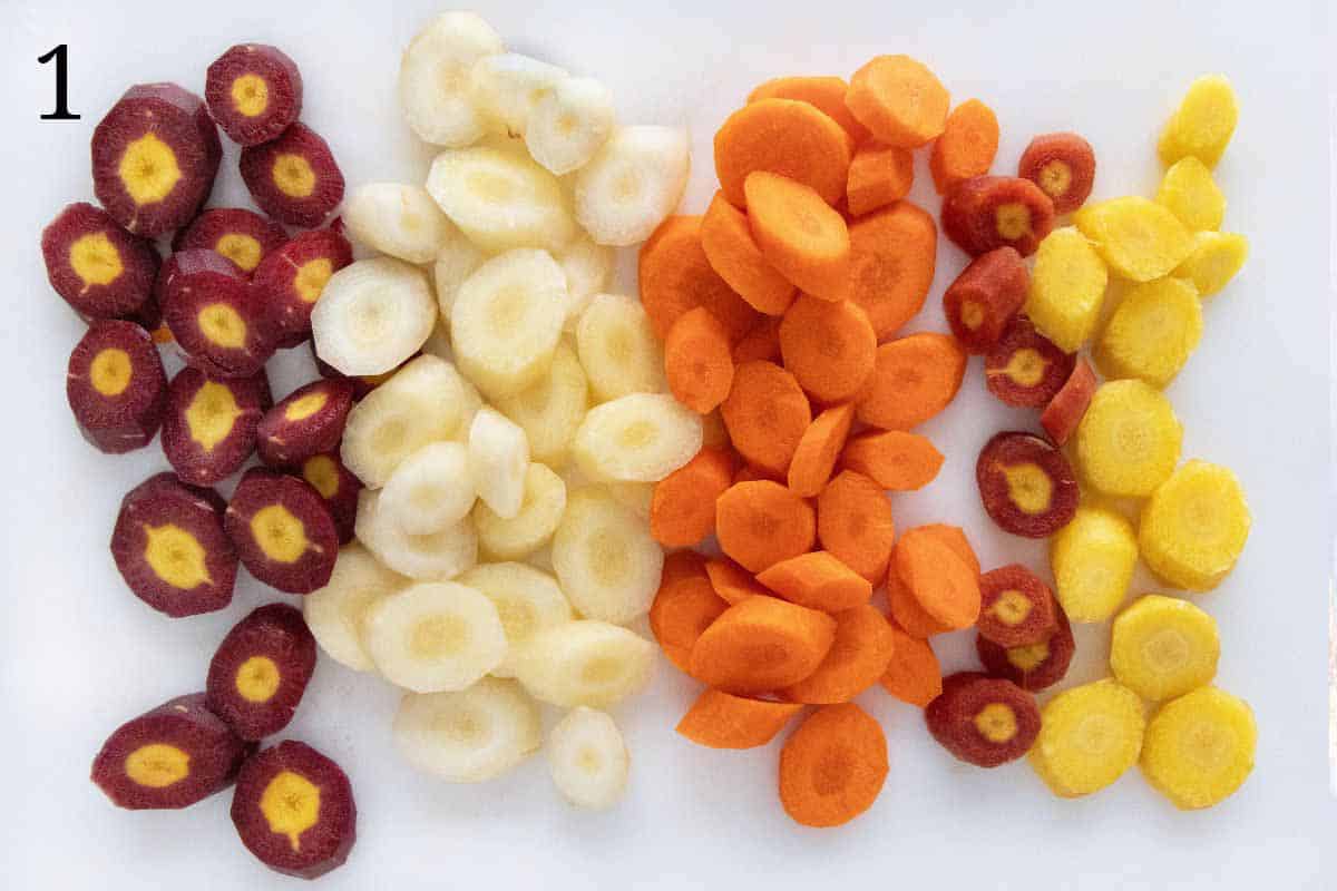 Sliced rainbow carrots on a white cutting board.