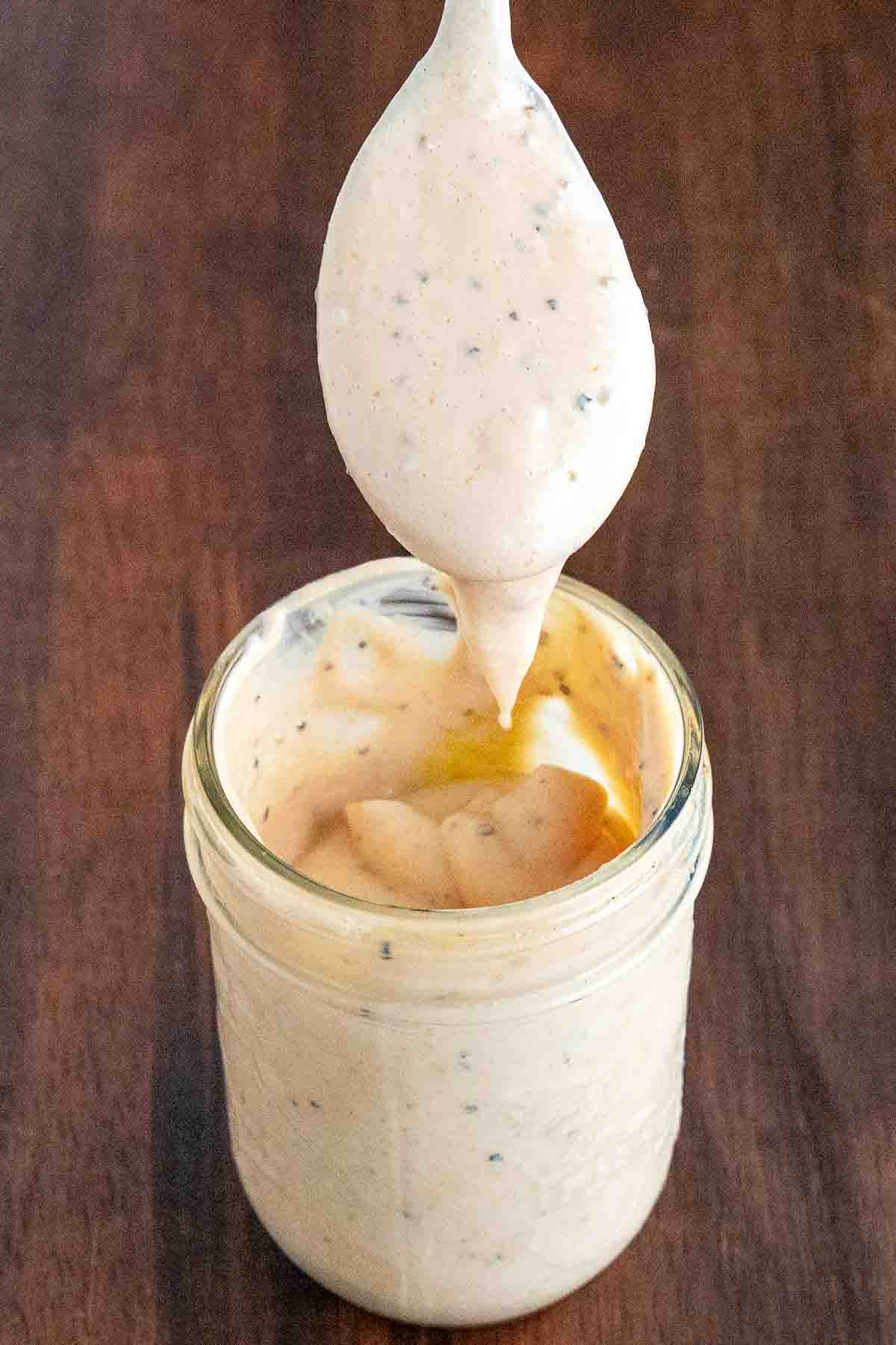Cane's chicken sauce in a glass jar with a spoon coming out.