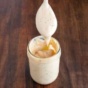 Cane's chicken sauce in a glass jar with a spoon coming out.