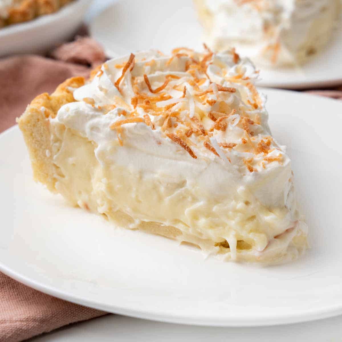 Slice of coconut cream pie on a white plate.